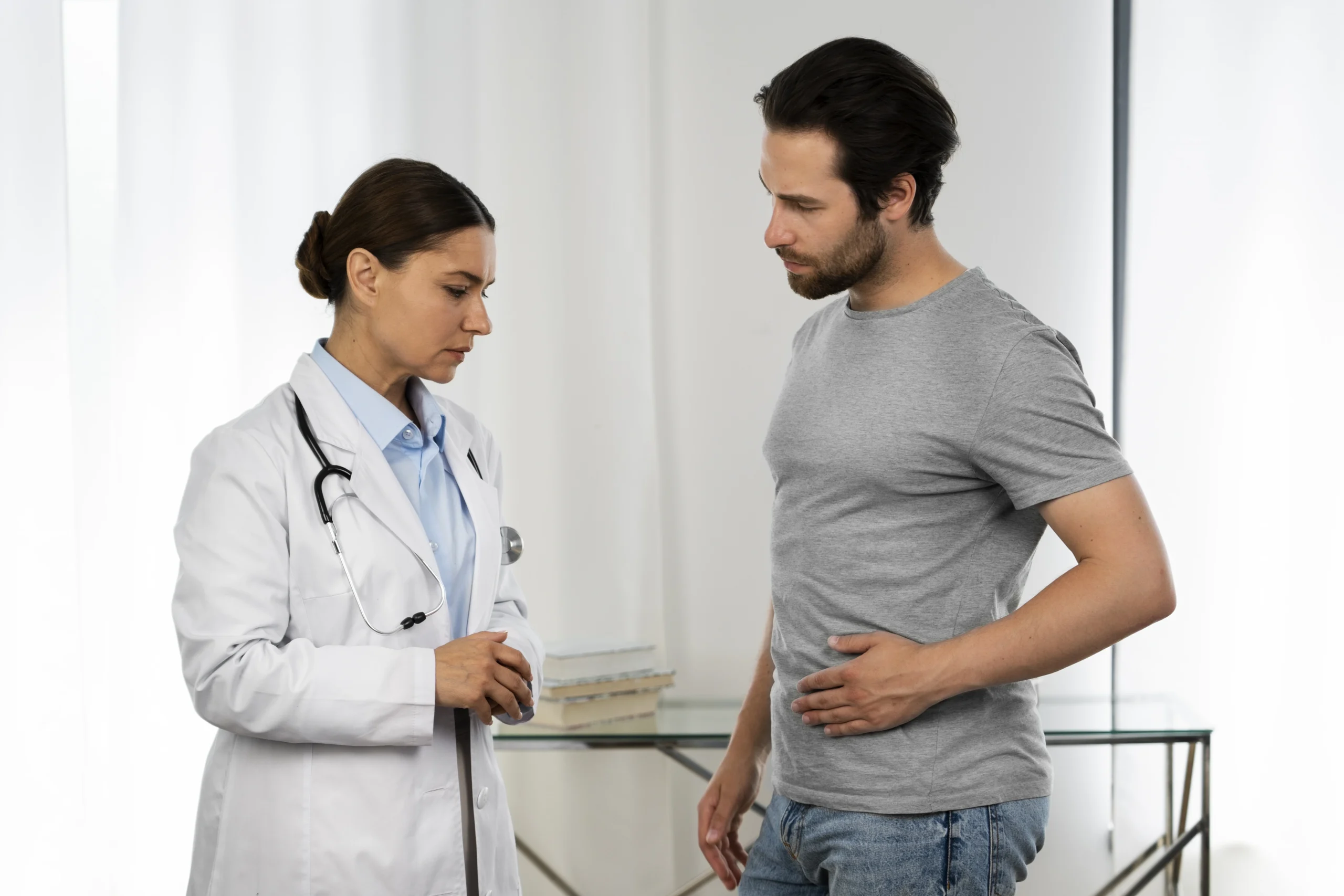 Female urologist consulting male patient with abdominal discomfort at Ashtavinayak Multispeciality Hospital, Panvel – expert urology care and diagnosis.
