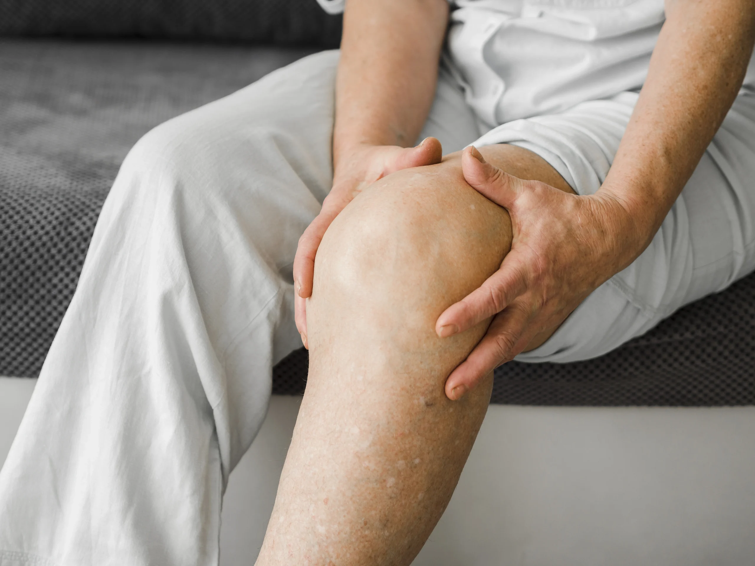Elderly patient holding knee in pain – expert knee replacement care at Ashtavinayak Multispeciality Hospital, Panvel for improved mobility and relief.