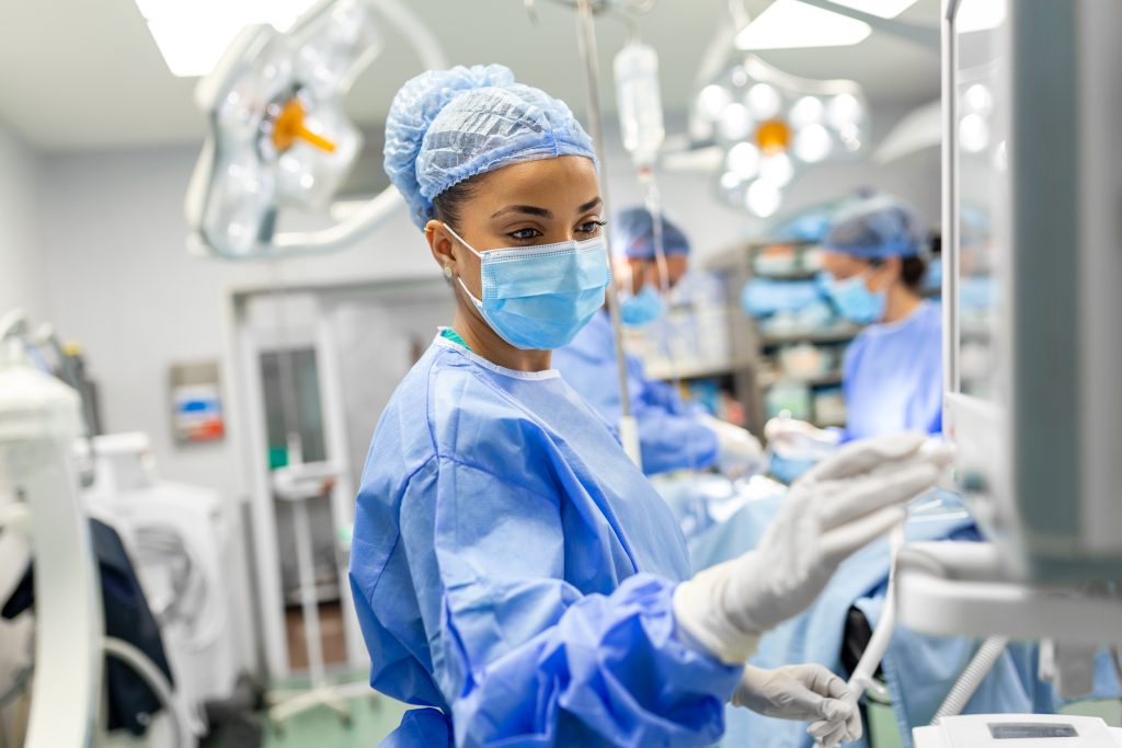 Medical staff in protective gear monitoring equipment in an intensive care unit (ICU)